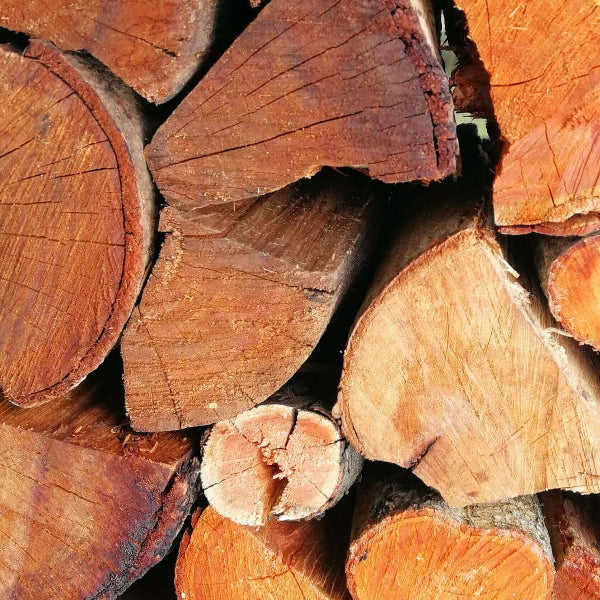 Close-up of seasoned Black Wattle firewood logs in Cape Town, showing its distinctive reddish-orange grain